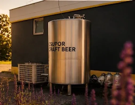 Csupor Craft Beer feliratú rozsdamentes tartály a főzde falánál, naplementében