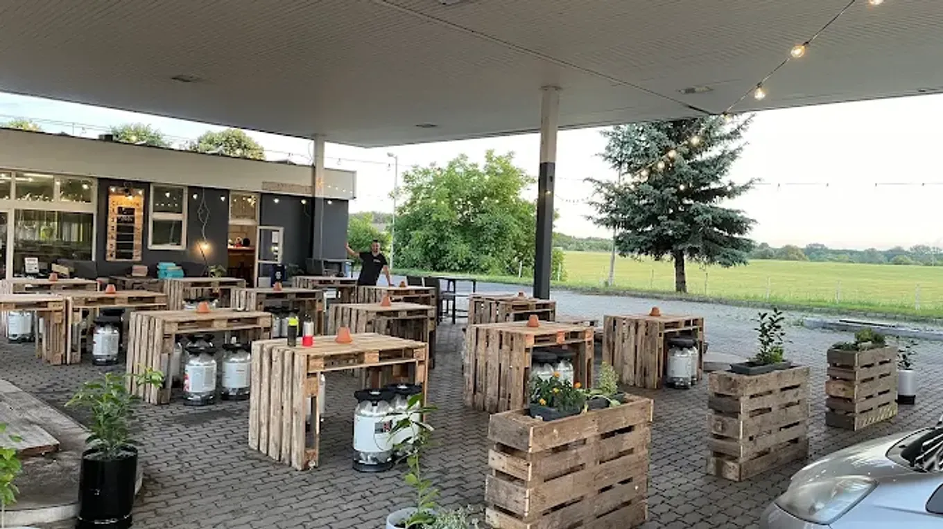 A Csupor terasz raklapasztalokkal és fényfüzérrel a kútbeálló alatt